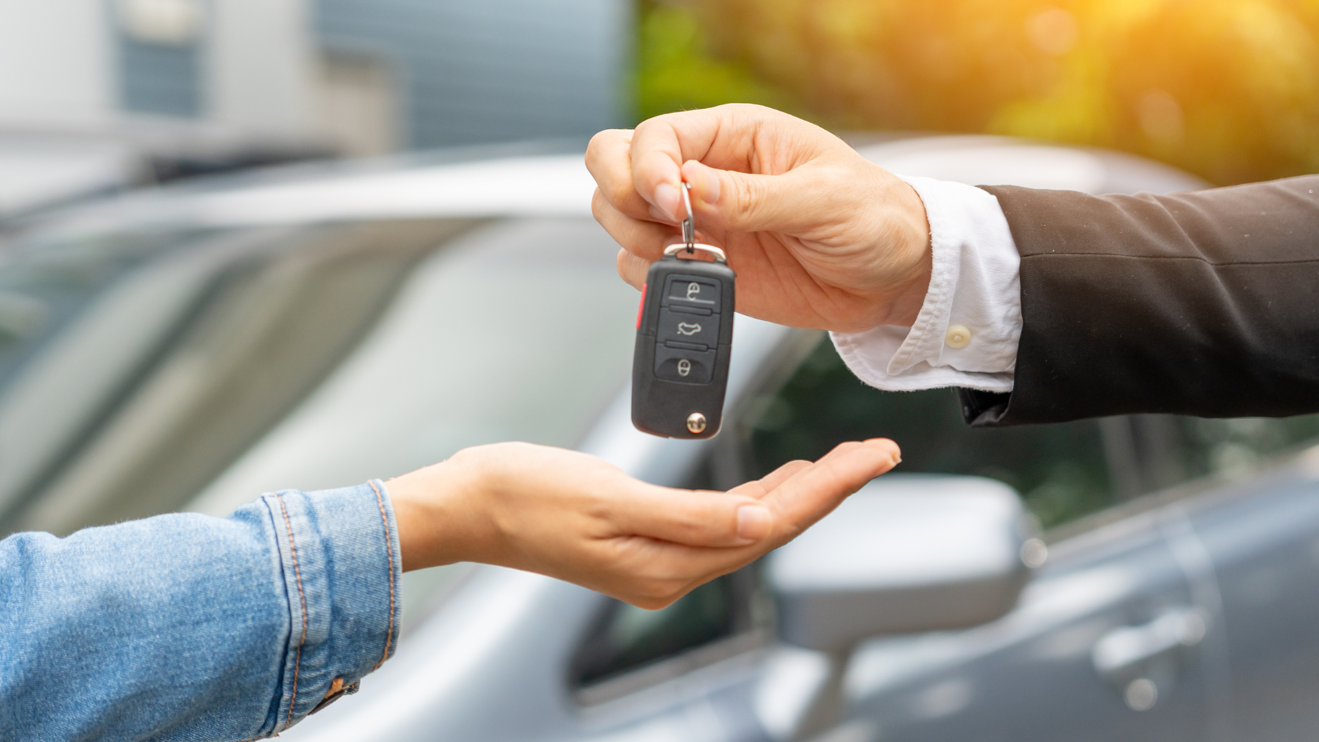 A person hands over car keys to another person, representing Ituran's vehicle security and stolen vehicle recovery services that protect connected cars and provide peace of mind for vehicle owners.
